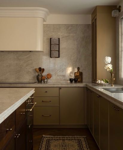 Olive green kitchen cabinetry with stone backsplash, brass hardware, and herringbone wood floor