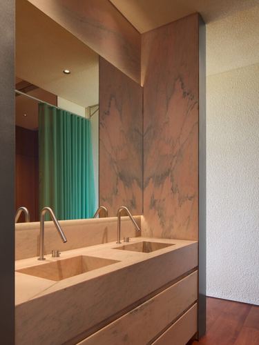 Bathroom with pink-veined marble vanity, double sinks, and mirror reflecting a teal shower curtain