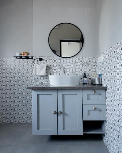 Bathroom vanity with round black mirror, vessel sink and patterned tile wall