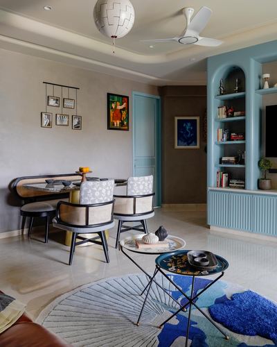 Living room with blue arched shelving, cane armchairs, round layered rugs, and pendant globe light