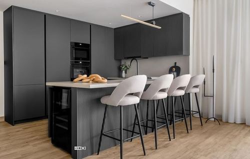 Dark matte kitchen with fluted island, four beige bar stools, and wood flooring