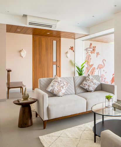 Blush pink living room with grey sofa, wooden door, and flamingo mural visible through glass wall