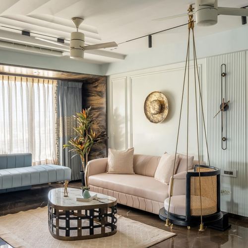 Living room with blush sofa, hanging cane swing, marble coffee table and paneled wall