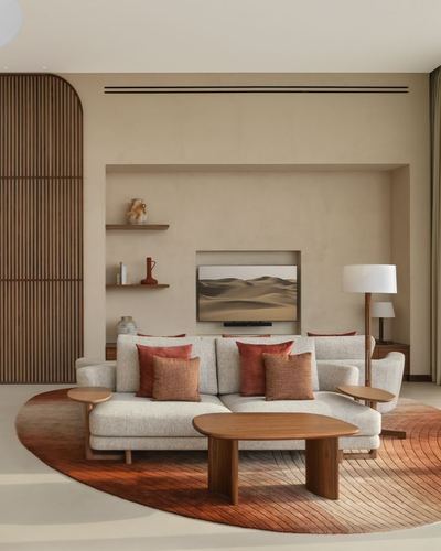 Beige living room with terracotta pillows, wood slat screen, and round ombre rug