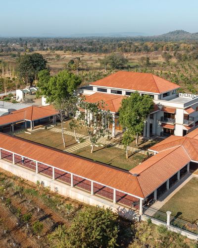 Aerial view of a sprawling farmhouse with terracotta roofs around a landscaped courtyard, surrounded by farmland