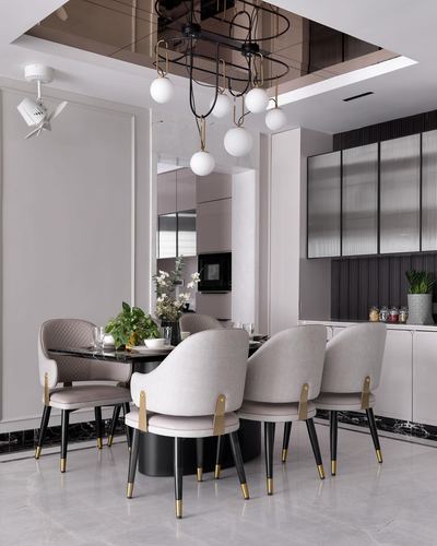 Round dining table with beige upholstered chairs under a cluster of globe pendant lights