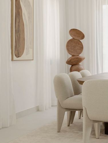 Dining nook with boucle chairs, sheer curtains, abstract art, and a stacked sculptural object