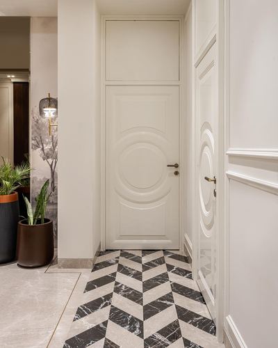 Foyer with paneled cream doors, circular motif, and black-and-white chevron marble floor