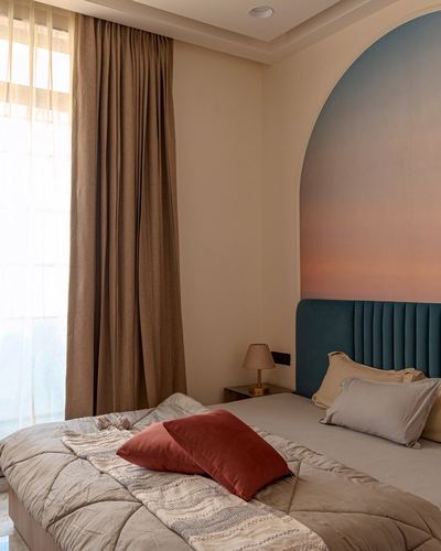 Bedroom with arched sunset-gradient niche behind a teal velvet headboard and terracotta accent pillow
