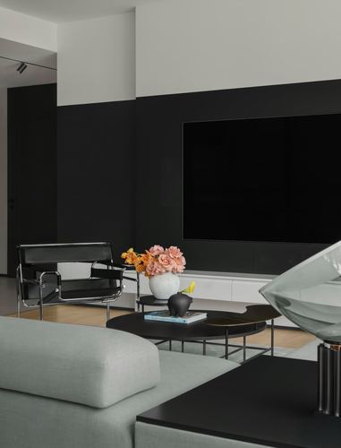 Minimalist living room with black feature wall, wassily chair, and kidney coffee table