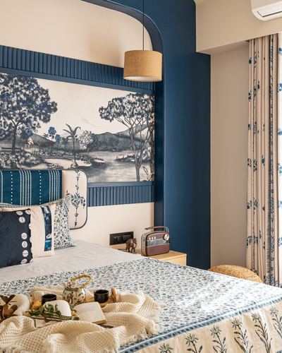 Bedroom corner with painted scenic mural headboard, blue arch, and block-print bedding