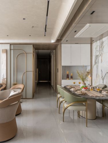 Neutral-toned dining area with oval marble table, green leather chairs, and arched brass screen