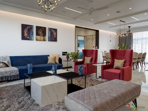 Living room with navy sofa, red wing chairs, marble coffee tables and triptych wall art