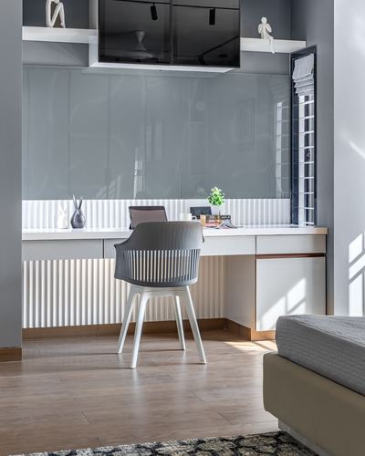 Grey and white study nook with fluted paneling, white chair, and wooden floor