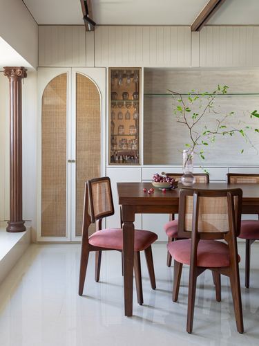 Dining room with cane-backed chairs, wood table, and arched cane storage doors