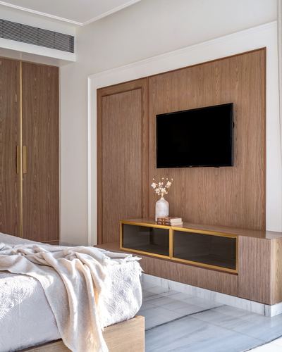 Bedroom with wood-panelled TV wall, brass-trimmed console, and marble flooring