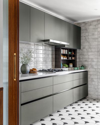 Sage green modular kitchen with tiled backsplash and patterned black-and-white floor