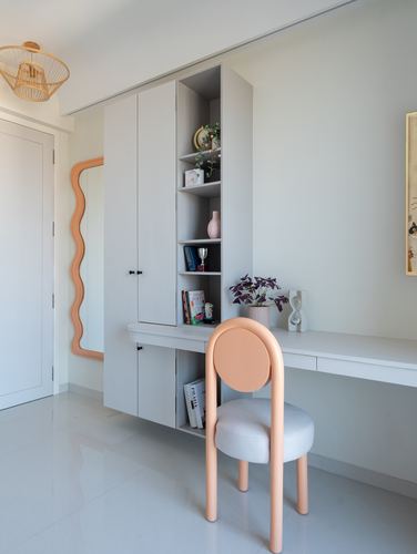 Grey built-in shelving desk unit with peach chair and wavy mirror in minimalist bedroom