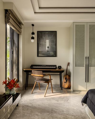 Bedroom corner with wooden desk, keyboard, guitar, framed art and marble floor