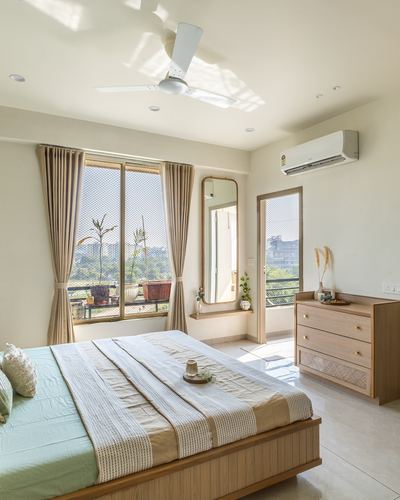 Pastel bedroom with wooden bed, arched mirror, and balcony window overlooking greenery