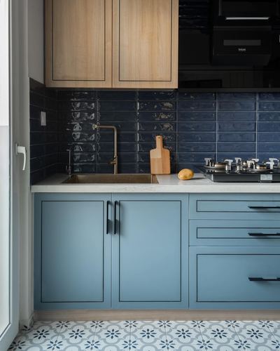 Kitchen with blue cabinets, navy tile backsplash, wood upper cabinets, and patterned floor tiles