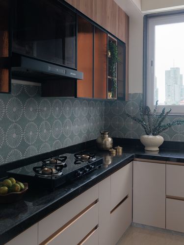 Modern kitchen corner with patterned backsplash, dark countertop, and city view through window