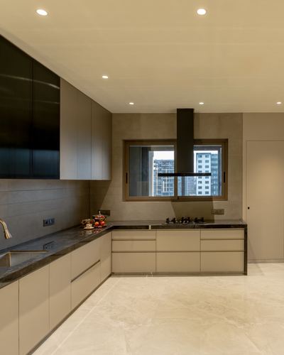 Modern L-shaped kitchen with dark stone counters, taupe cabinetry, and a city-view window