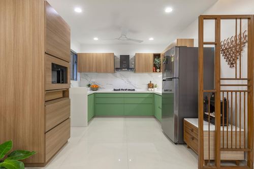 U-shaped kitchen with wood cabinetry, green lower units, marble-look backsplash, and steel fridge
