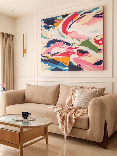Beige living room with curved sofa, wood coffee table, and large abstract painting above