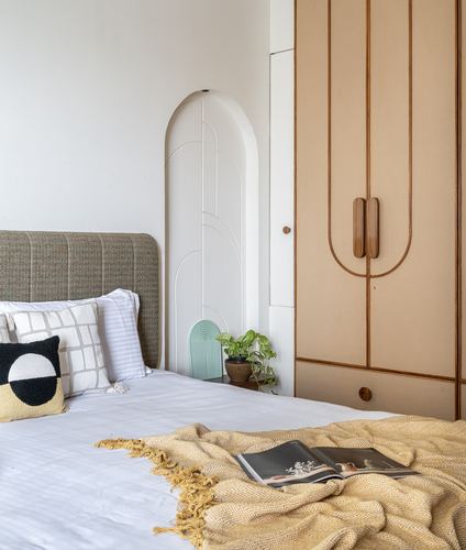 Bedroom with tufted headboard, arched wall panel, and wooden wardrobe with curved handles