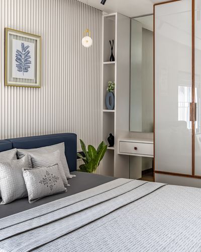 Bedroom corner with fluted wall panelling, navy leather headboard, and built-in dressing shelf