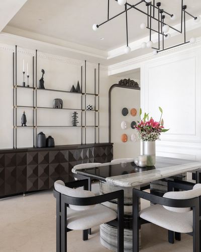 Dining room with marble-topped black table, black chairs, open shelving and sculptural chandelier