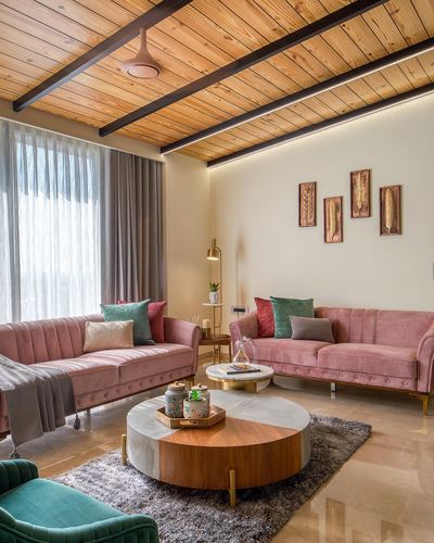 Living room with two pink velvet sofas, wood-slat ceiling, and round marble-wood coffee table