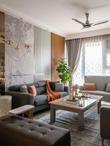 Grey living room with mural wall, brass bird decor, fluted wood panel, and marble coffee table