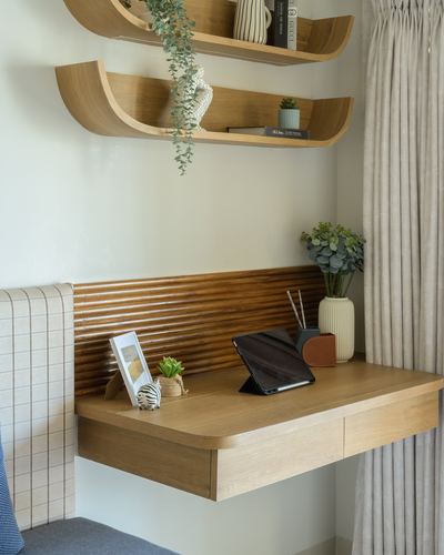 Floating wooden desk with fluted panel backdrop under curved wall shelves holding plants and books