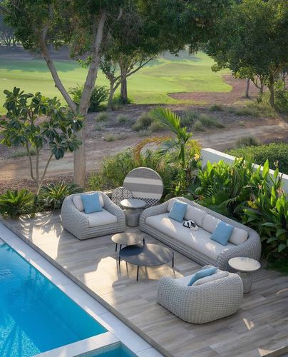 Elevated view of a poolside terrace with woven lounge furniture overlooking a golf course