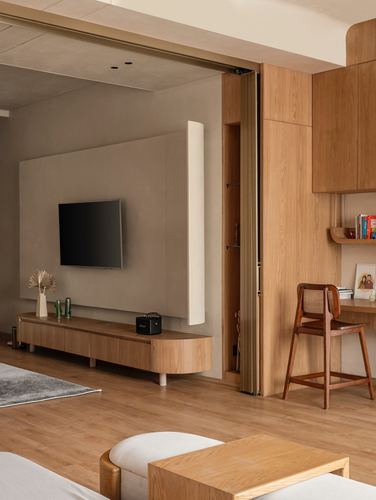 Living room with wood tv console, curved sconce, and study nook behind folding wood doors