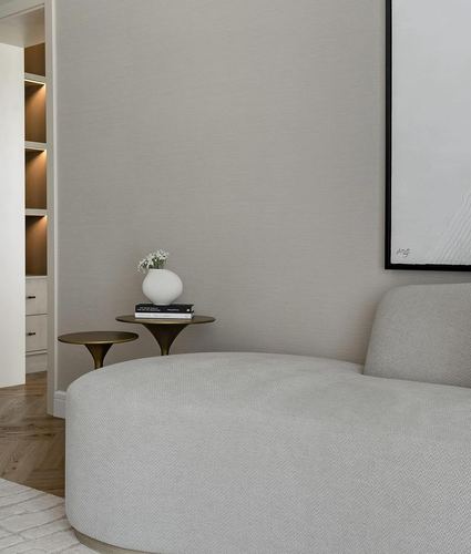 Corner of a neutral bedroom with curved bouclé sofa, brass side table and lit shelving nook