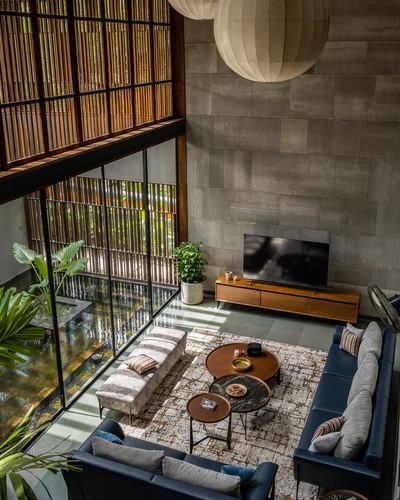 Elevated view of double-height living room with reflecting pool, slatted screens, and layered seating