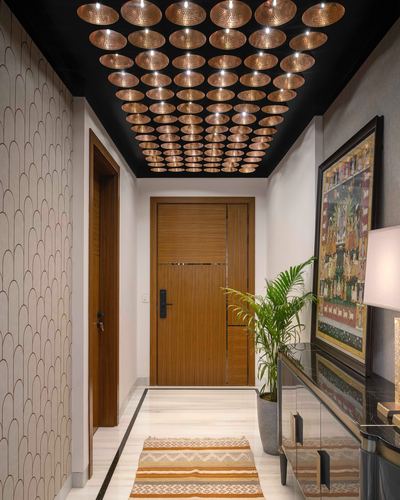 Foyer corridor with copper disc ceiling, wooden door, patterned wallpaper and framed painting