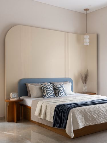 Bedroom with arched fluted panel wall, blue upholstered bed, and round pendant light