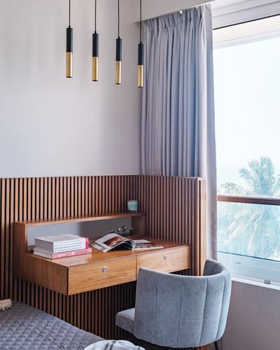 Fluted wood headboard extending into a built-in desk beside a window with sea view
