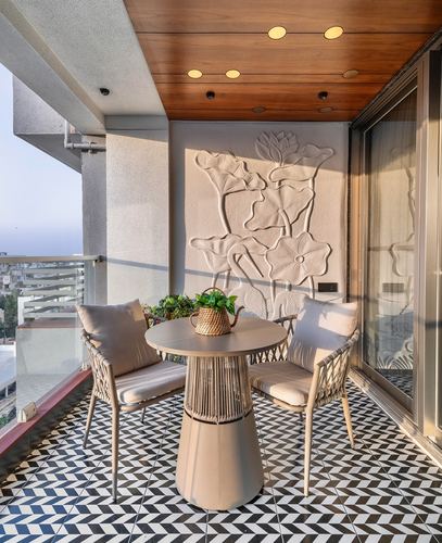 Balcony with patterned tile floor, wood ceiling, and a floral plaster relief wall behind two woven chairs