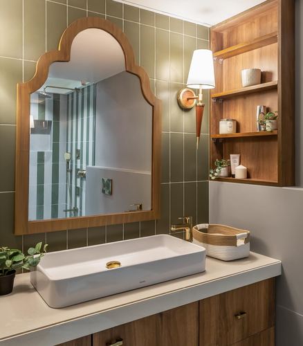 Bathroom vanity with arched wooden mirror, vessel sink, olive tile wall, and open wood shelving