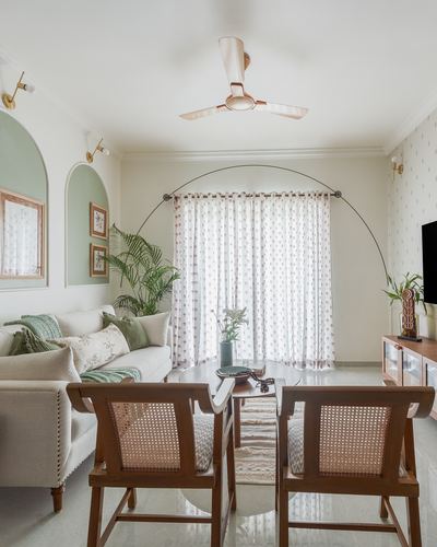 Living room with cane chairs, arc lamp, arched green niches and sheer floral curtains