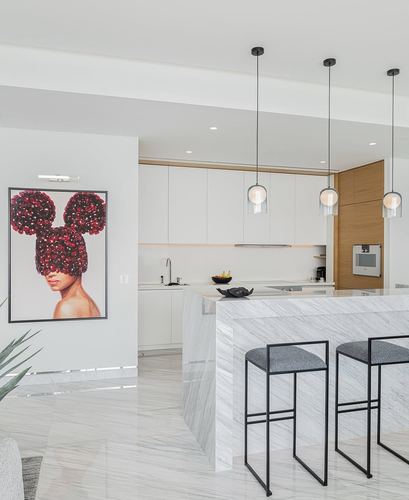 Modern white kitchen with marble waterfall island, glass pendant lights, and bold floral portrait artwork