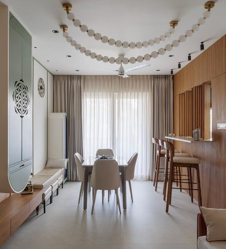 Dining space with fluted wood wall, sheer curtains, beaded ceiling garlands, and mint cabinetry