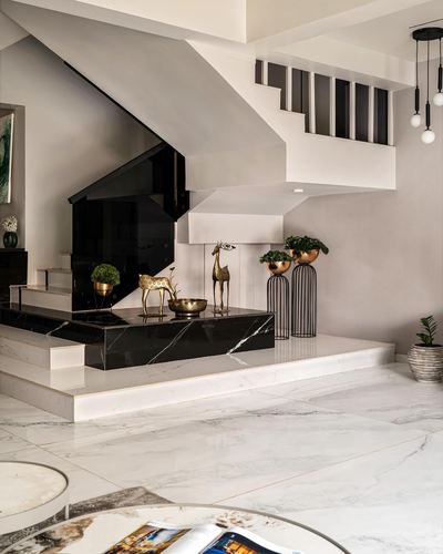 White marble foyer beneath sculptural staircase with black glass balustrade and brass deer figurines