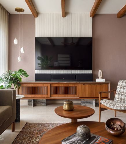 Living room with wooden media console, fluted panel TV wall, exposed beams, and patterned armchair