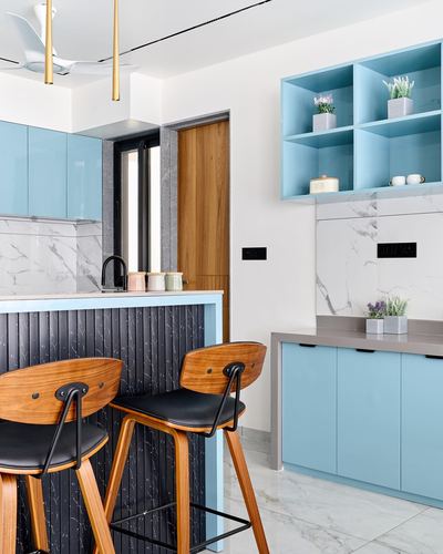 Blue kitchen with fluted black island, wooden bar stools, and marble-look backsplash